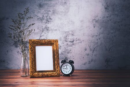 Picture frame and flowers and clock on wooden table. Poster product design styledの写真素材