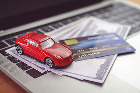 Credit card, Car model and Notebook on wooden desk. shopping online and car payment by using laptop