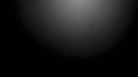 A dark, abstract image with gradient from black to gray, creating mysterious and moody atmosphere. central light area suggests depth and focusの素材