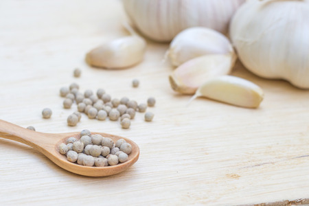 White pepper on wooden spoon with garlicsの写真素材