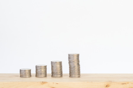 Coins stack on wooden table isolated on white backgroundの写真素材