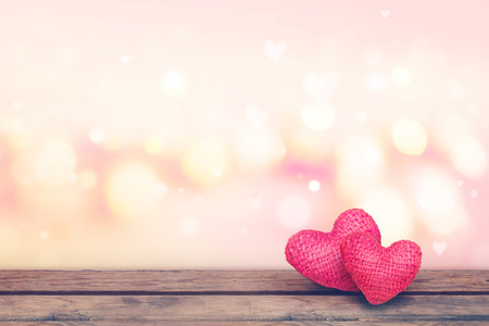 Soft focus red knitted hearts on wooden table with pink bekeh background-Valentine day concept.の写真素材
