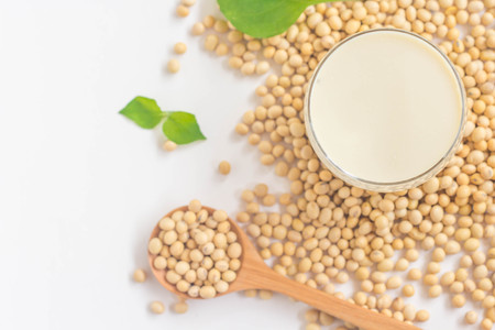 Top view image of a glass of soy milk with soybeans on wooden spoon and leaves isolated on white background-Selective focusの写真素材