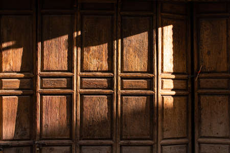 Sunset light and shadow on the old wooden folding door surface.の写真素材