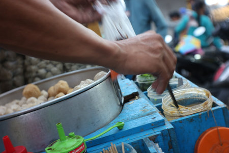 The seller of  meatballs, kojek is serving buyers using a cart on a motorbike around selling his wares.の写真素材