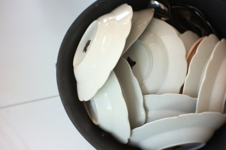 Pile of white and black ceramic tableware in black bowl.