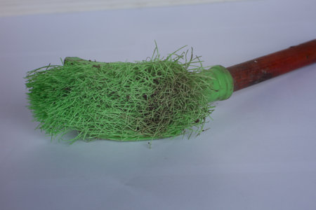 Green broom for cleaning on a white background, closeup of photo