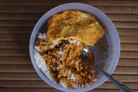 Top view of omelet with rice in bowl on wooden tableの写真素材