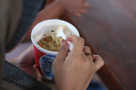 Asian woman eating noodles with chopsticks in a restaurant.の写真素材