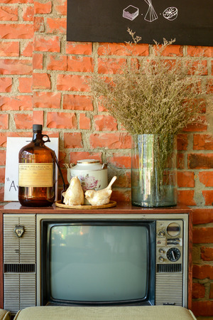 Vintage room with Brick wall, retro TV, old bottle, ceramic birds, teapot and Dry plant in vaseの写真素材