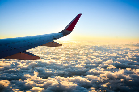 airplane flying over clouds with evening sky - view from window of airplaneの写真素材