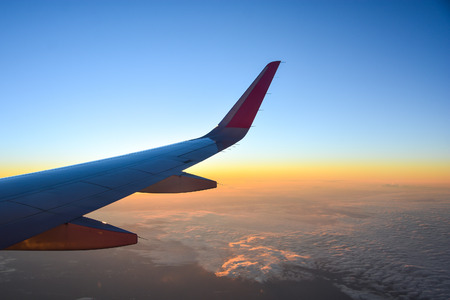 airplane flying over clouds with evening sky - view from window of airplaneの写真素材