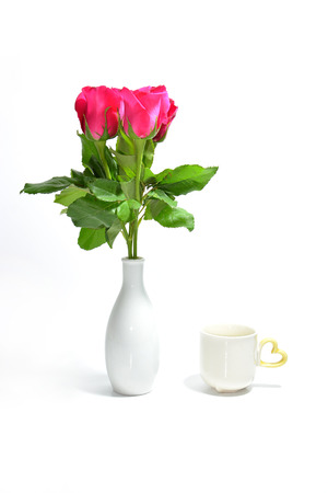 tea cup of love and pink rose in vase isolated on white backgroundの写真素材