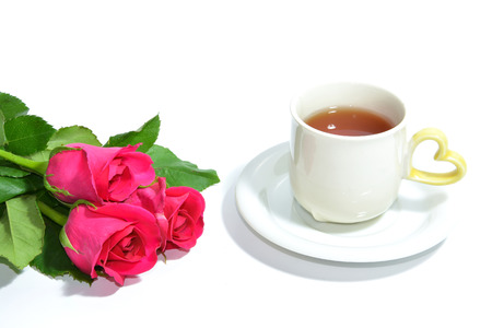 Tea cup of love and three pink roses isolated on white backgroundの写真素材