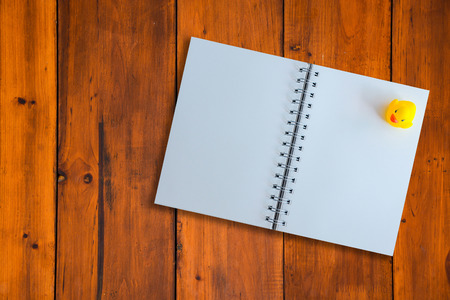 white page of notebook and yellow duck on wood patternの写真素材