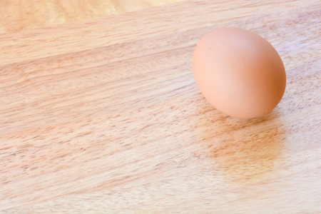 closeup of chicken egg placed on wooden tableの写真素材