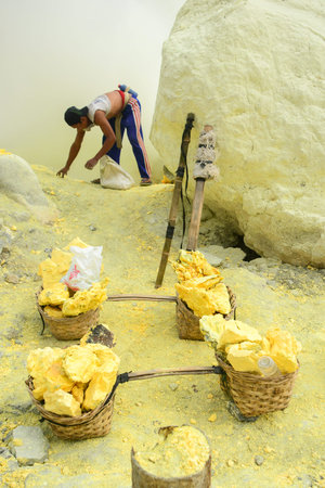 KAWAH IJEN INDONESIA  JANUARY 22 2013 : Miner collect sulfur sulphur into baskets in fumes of toxic volcanic gas from the sulfur mines in the crater of the active volcano of Kawah Ijen East Java Indonesia.のeditorial素材