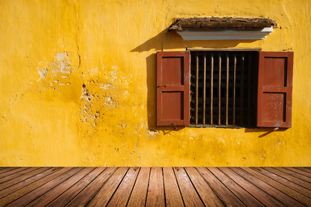 opened antique window on the old grunge yellow wall and wood floor pattern for backgroundの写真素材