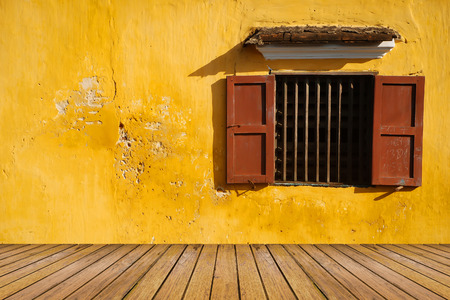 opened antique window on the old grunge yellow wall and wood floor pattern for backgroundの写真素材