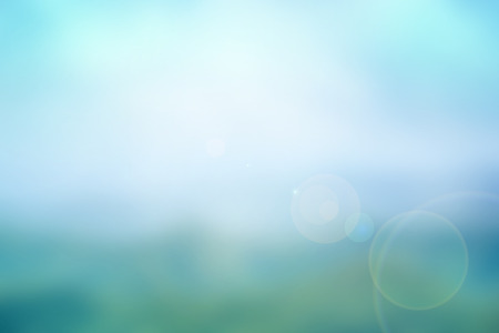 Abstract nature blurred background in blue-turquiose tone with bright sunlight, flare and bokeh effectの写真素材