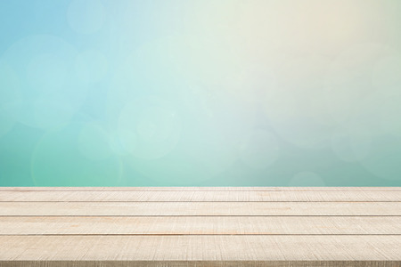 Beige wood table top panel on pastel blurred background in blue-turquoise tone with bright sunlight and flare, use for display or montage products for advertisement in natural summer conceptの写真素材