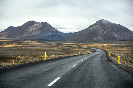 Empty road leading to black mountains, Beautiful dramatic landscape in early winter of Iceland