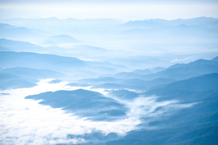 Beautiful blue layers of mountain range landscape from top view in majestic fog of winterの写真素材