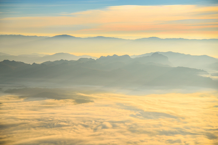 Beautiful layers of mountain range landscape with winter sky from top view in majestic sunrise and fogの写真素材