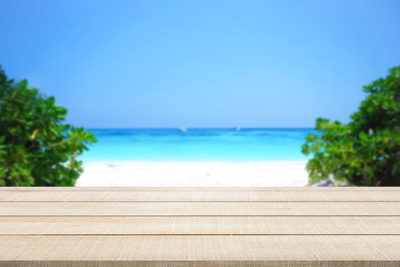Beige wood table top panel on beautiful beach, sea and sky blurred background, use for display or montage products for advertisement in summer holiday conceptの写真素材