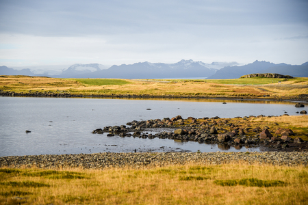 Lake, yellow field and mountain landscape in winter of Southeast Icelandの写真素材