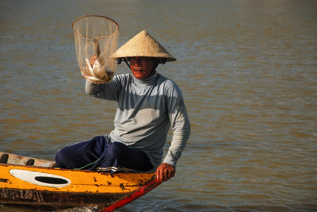 HOI AN, VIETNAM - OCTOBER 24, 2012 : Vietnamese fisherman show a traditional fishing net with fishes that he caught in the river at Hoi An, Vietnamのeditorial素材