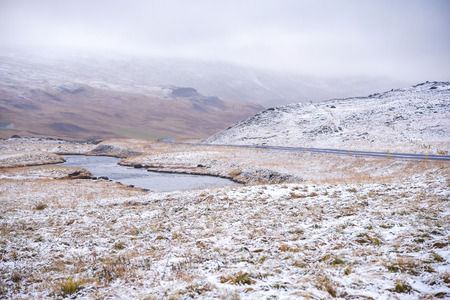 Scenic landscape with field, mountain, snow and dramatic sky in winter of Icelandの写真素材