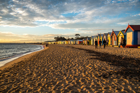MELBOURNE, AUSTRALIA - JULY 18, 2016 : Tourists walk pass colorful bathing boxes at Brighton Beach near Melbourne, Australia.のeditorial素材