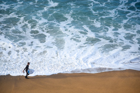 TORQUAY, AUSTRALIA - JULY 20,2016 : surfer man on the beach with texture of turquoise-white water wave in the sea from top view at Bells beach, Torquay, Australia.のeditorial素材