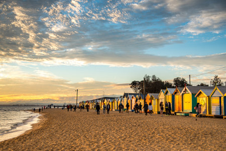 MELBOURNE, AUSTRALIA - JULY 18, 2016 : Tourists walk pass colorful bathing boxes at Brighton Beach near Melbourne, Australia.のeditorial素材