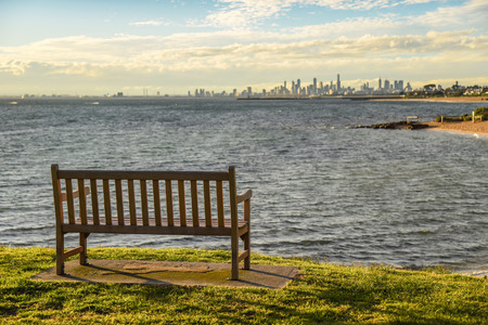 empty wooden bench on green field with beautiful sunset sky near Brighton beach in Melbourne, Victoria, Australiaの写真素材
