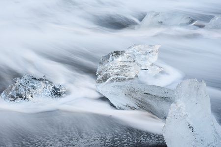 Icebergs with movement of water wave on black volcanic sand beach near Jokulsarlon glacier lagoon, Southern Icelandの写真素材
