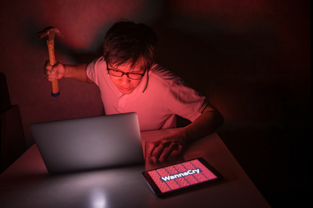 Ransomware victim angry with file lock on his computer laptop try to smash his laptop computer with hammer. Internet security system conceptの写真素材