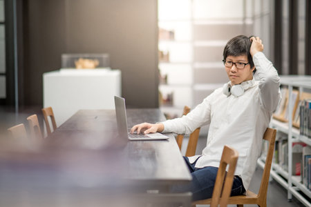 Young Asian university student working with laptop computer in library, self learning and college...