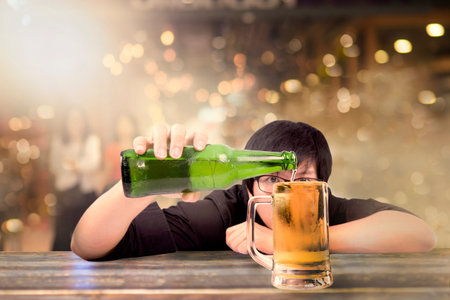 Young male hand holding beer bottle and fill the glass, Asian man pouring beer on bar in pub party