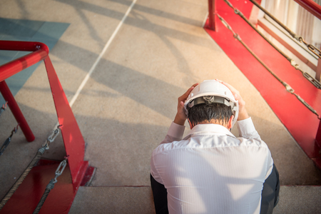 Engineer or Architect feeling tired and headache with his job while wearing protective equipment safety helmet at construction siteの写真素材