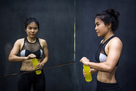 Young Asian athlete woman drinking sport drink or energy drink after exercise in fitness gym, healthy lifestyle conceptsの写真素材