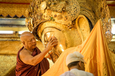 MANDALAY, MYANMAR - DECEMBER 24, 2016 : Senior monk wash the face of Mahamuni Buddha images every early morning at Mahamuni temple in Mandalay, Myanmar.のeditorial素材