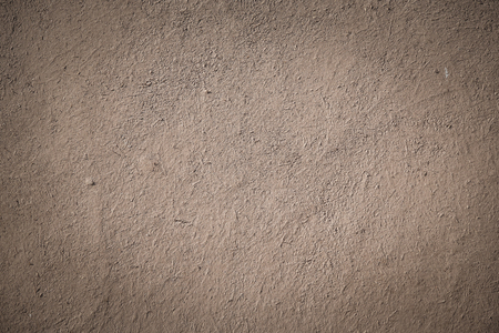 closeup detail of old beige-brown stucco clay wall, abstract rough surface background or backdrop with vignette effect in architectural material conceptの写真素材