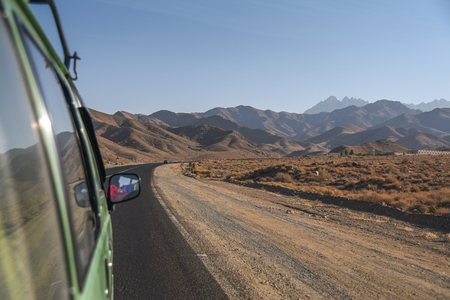 Green van on the road among scenic mountain and stone desert landscape in Iranの写真素材