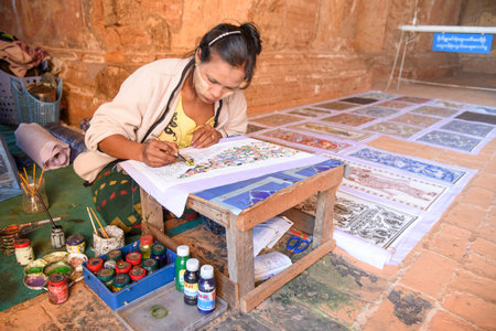 BAGAN, MYANMAR - DECEMBER 22, 2016 : Burmese artist woman draw a beautiful art painting inside the ancient pagoda of Bagan archaeological zone, Mandalay region, Myanmar.のeditorial素材