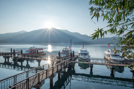 NANTOU, TAIWAN - FEBRUARY 13, 2017 : travel boats at pier and beautiful sunrise over mountain peak of Sun Moon Lake National Scenic Area, popular travel destination in Yuchi Township, Nantou, Taiwan.のeditorial素材