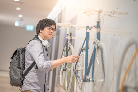 Young Asian man looking vintage bicycle at bike shop in department store, urban lifestyle conceptの写真素材