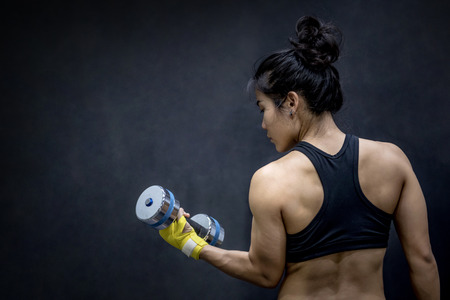 Young Asian woman lifting dumbbell in weight training fitness gym, sport exercise and muscular build, helathy lifestyleの写真素材