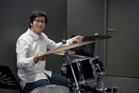 Young Asian man sitting with drum set in music practice room, musician lifestyle conceptsの写真素材